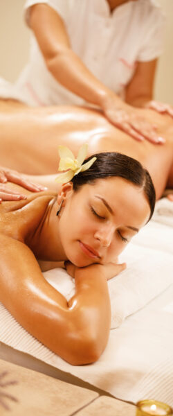Young couple relaxing during back massage at health spa. Focus is on young woman.